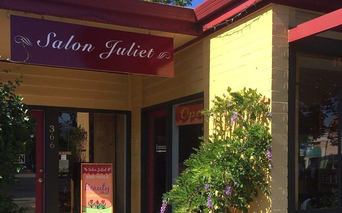 The Salon Juliet storefront on Lithia Way: a butter-yellow building with a plum sign and purple wisteria climbing beside the entrance
